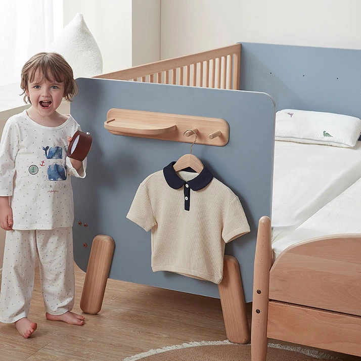 Built-in wooden shelf with hooks attached to the headboard of a convertible kids' bed, holding a small clock Built-in wooden shelf with hooks attached to the headboard of a convertible kids' bed, holding a small clock